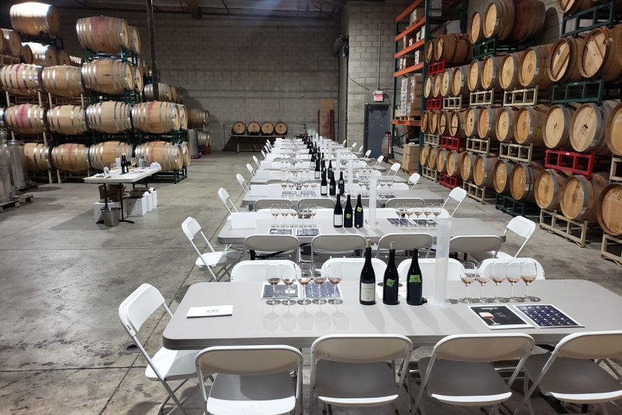 Multiple tables set in industrial wine barrel room for Team Building Wine Blending Trail for 100 guests